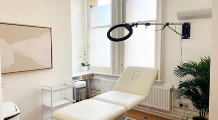 Peaceful treatment room at Aesthetic in Manchester, England, GB, featuring a plush cream chair and modern decor.