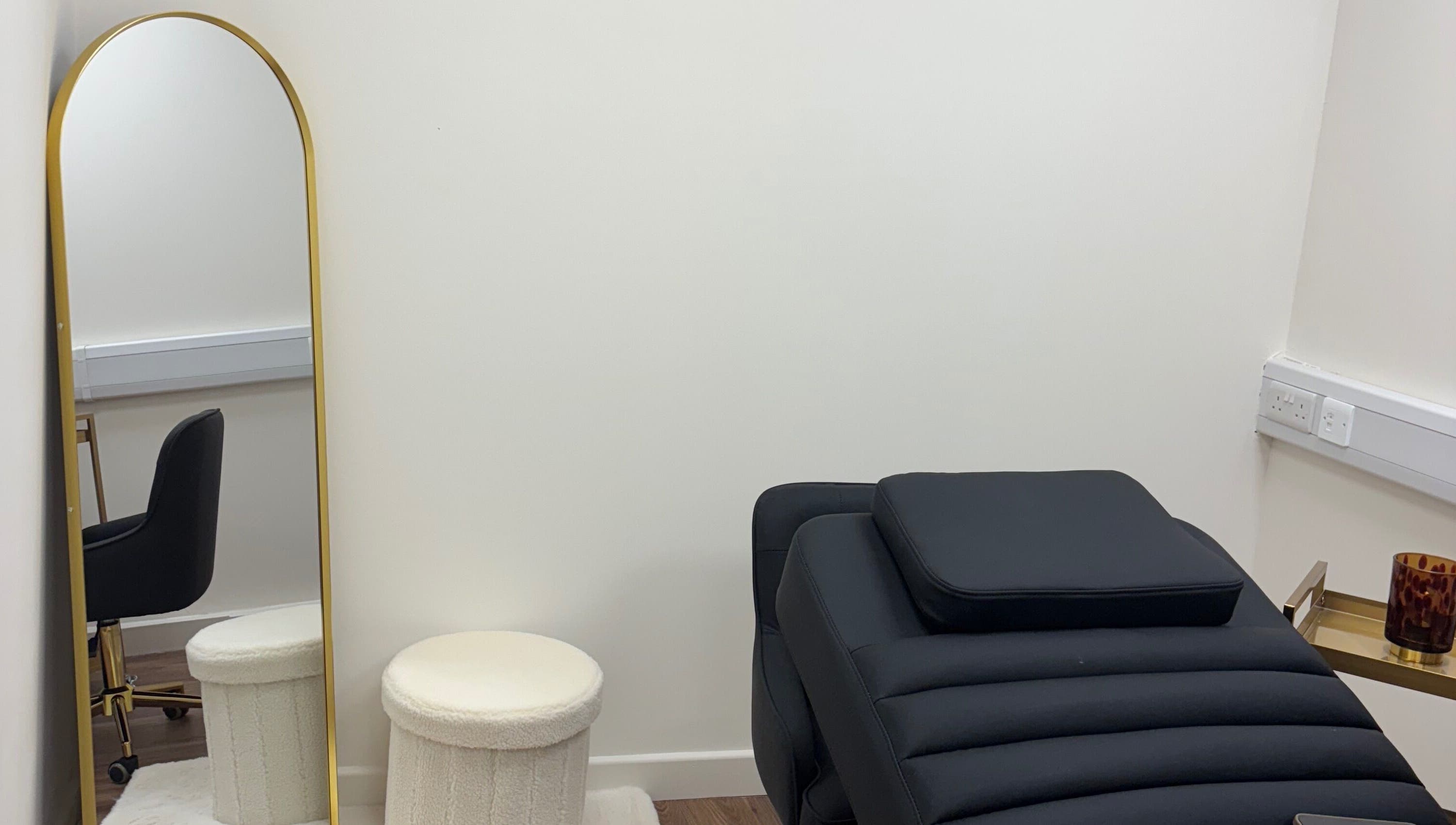 Stylish beauty treatment room at LashMuse in Galashiels, Scotland, GB with a black chair and gold mirror.