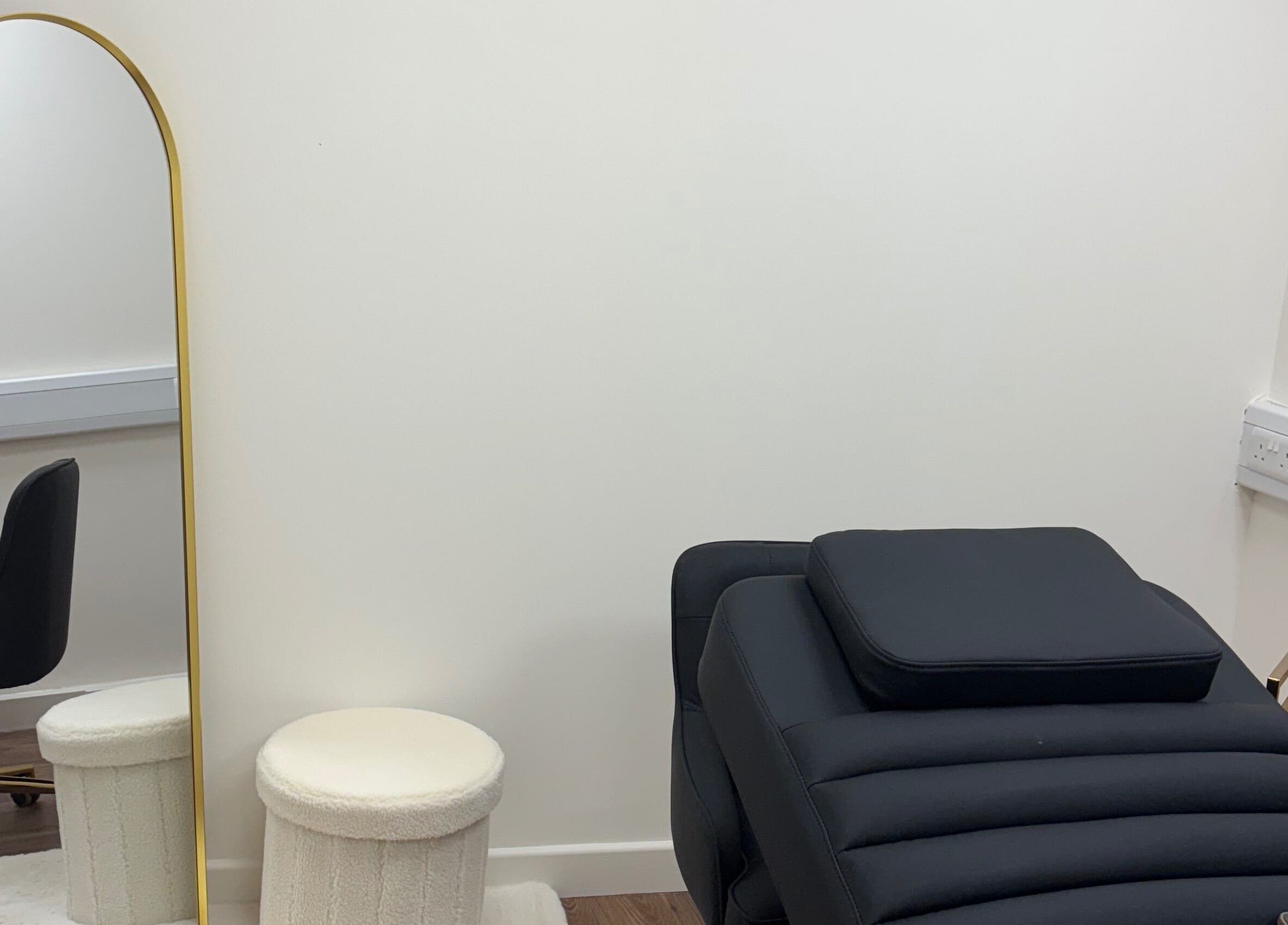 Stylish beauty treatment room at LashMuse in Galashiels, Scotland, GB with a black chair and gold mirror.