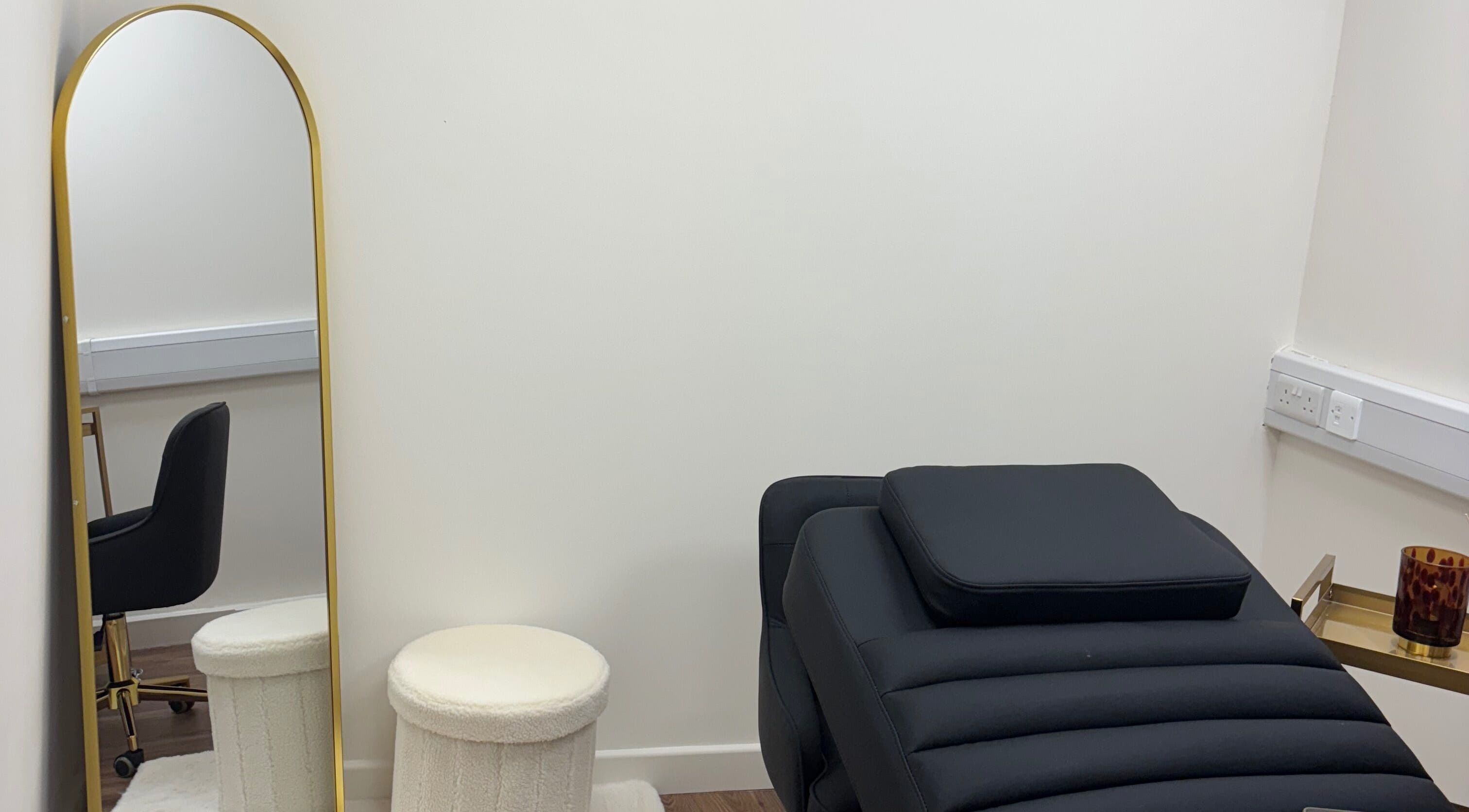 Stylish beauty treatment room at LashMuse in Galashiels, Scotland, GB with a black chair and gold mirror.