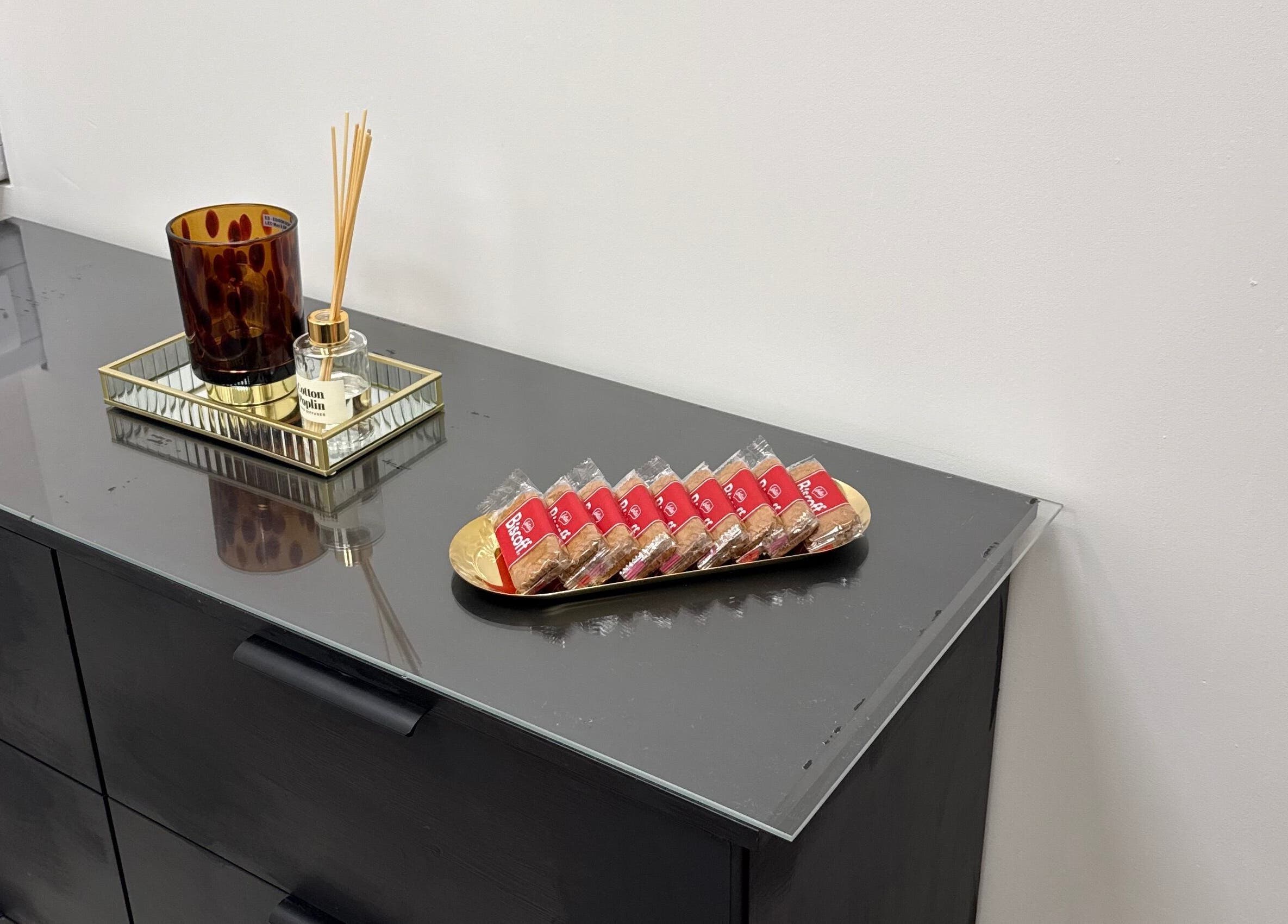 Elegant decor at LashMuse, Galashiels, Scotland with reed diffuser and cookies on black dresser.