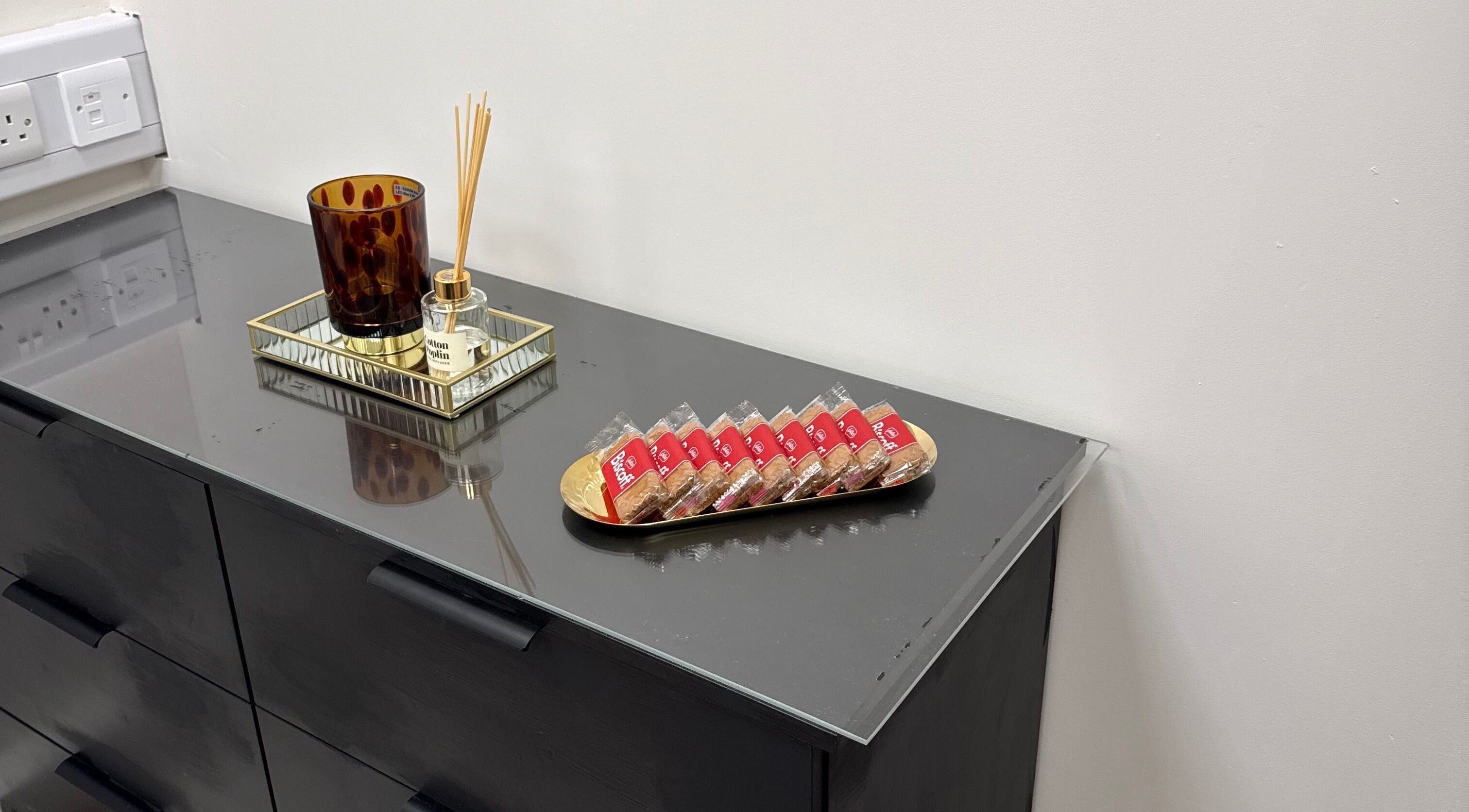 Elegant decor at LashMuse, Galashiels, Scotland with reed diffuser and cookies on black dresser.