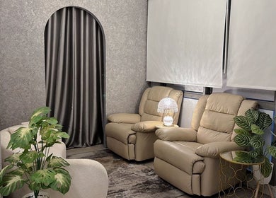Cozy lounge at Lashthetic8Bar in Kuala Lumpur with plush chairs and lush plants.