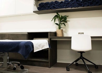 Treatment room at OA London in London, England, GB with a massage table, chair, and potted plant.