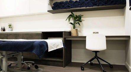 Treatment room at OA London in London, England, GB with a massage table, chair, and potted plant.