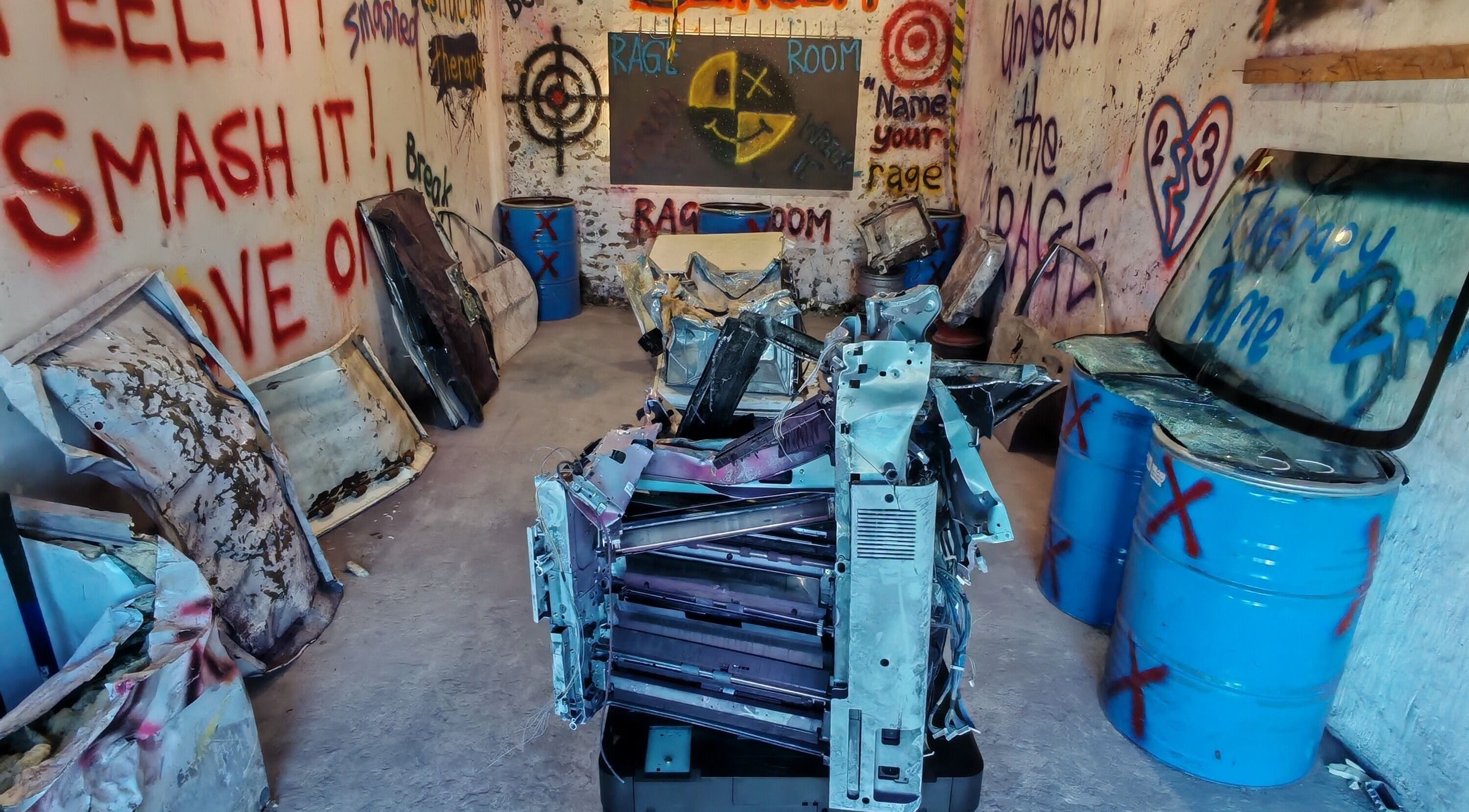 Interior view of Bliksem Rage Room, Gqeberha, Eastern Cape, ZA, showcasing creative wall graffiti and breakable items.