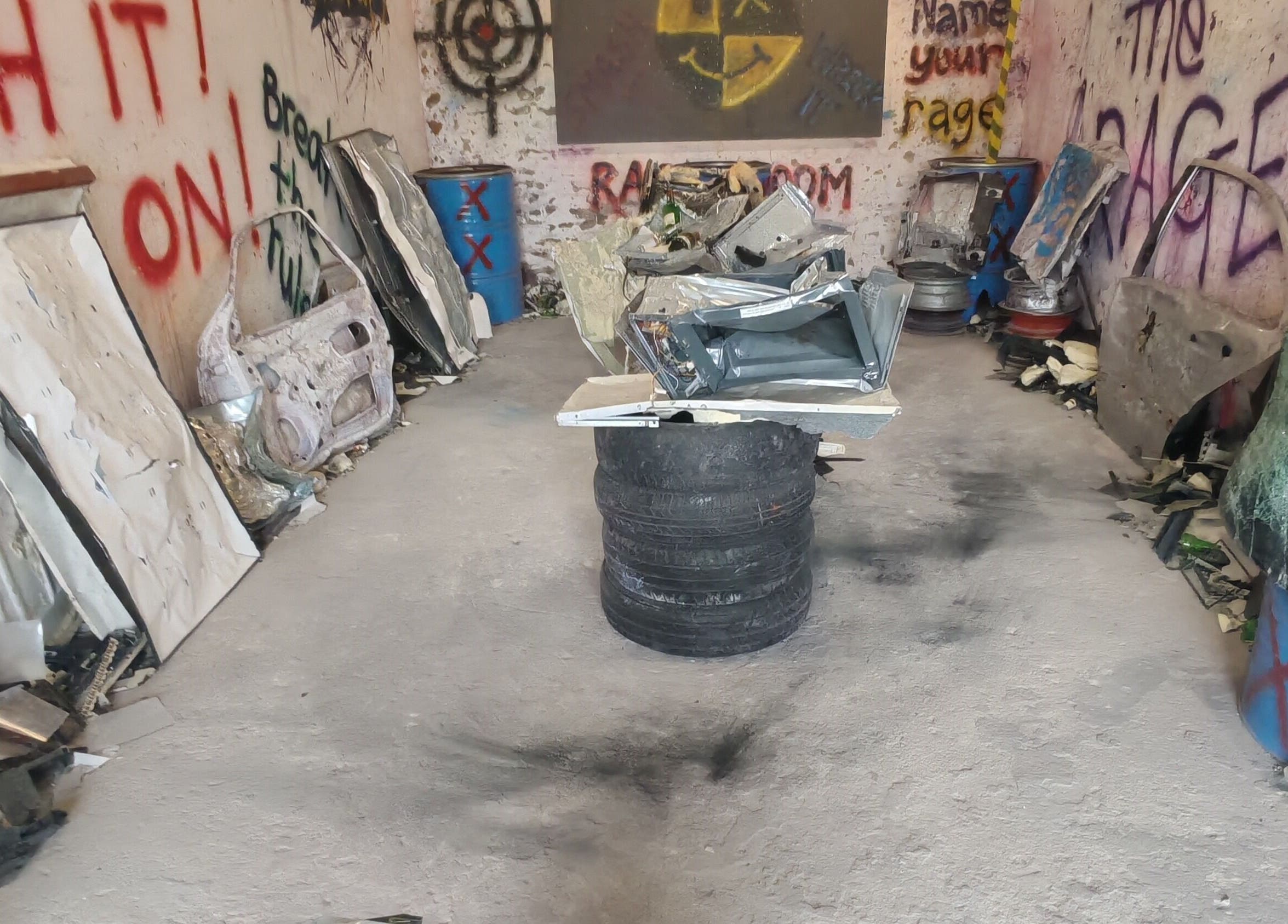 View of Bliksem Rage Room in Gqeberha, Eastern Cape, ZA, featuring smashed objects and vibrant graffiti.