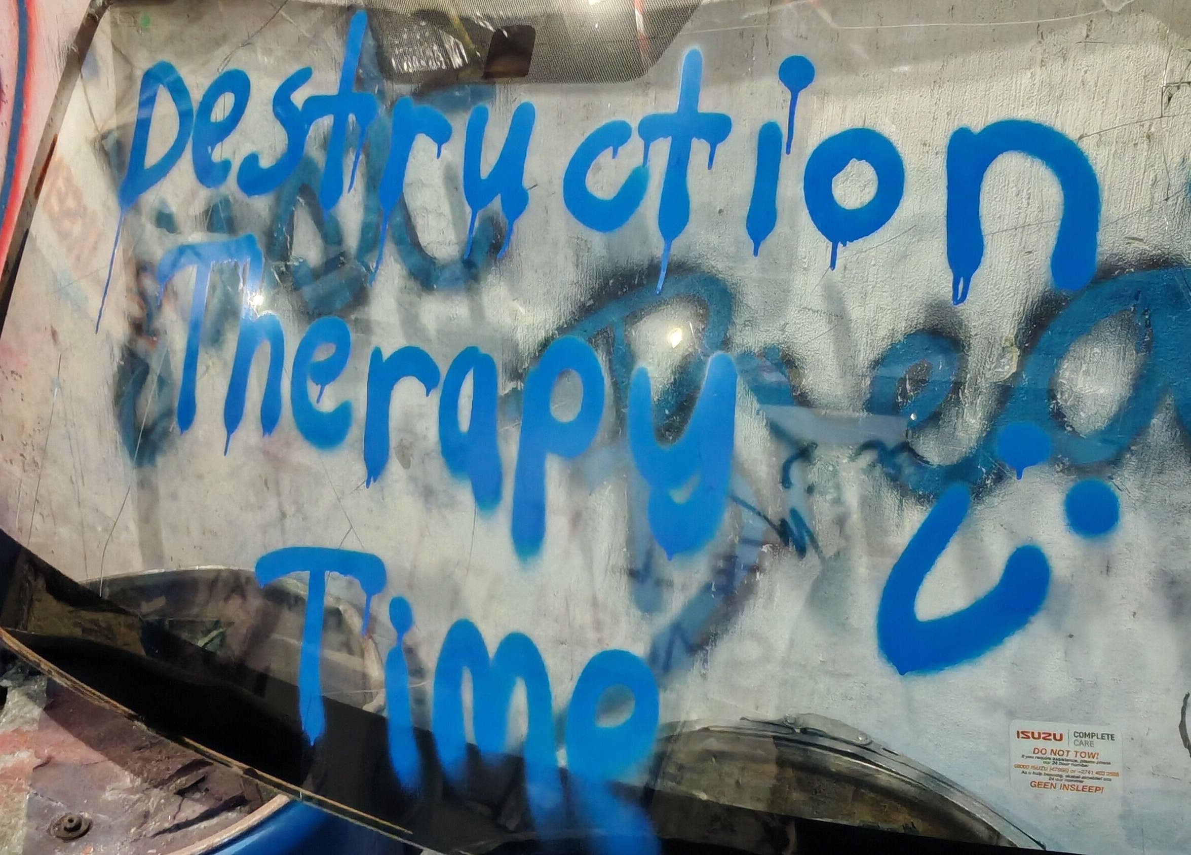 Blue graffiti on glass reading 'Destruction Therapy Time' at Bliksem Rage Room, Gqeberha, Eastern Cape, ZA.