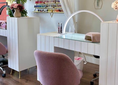 Elegant nail station at Blushed Miami, Palmetto Bay, FL, US, showcasing pink chairs and nail polish display.