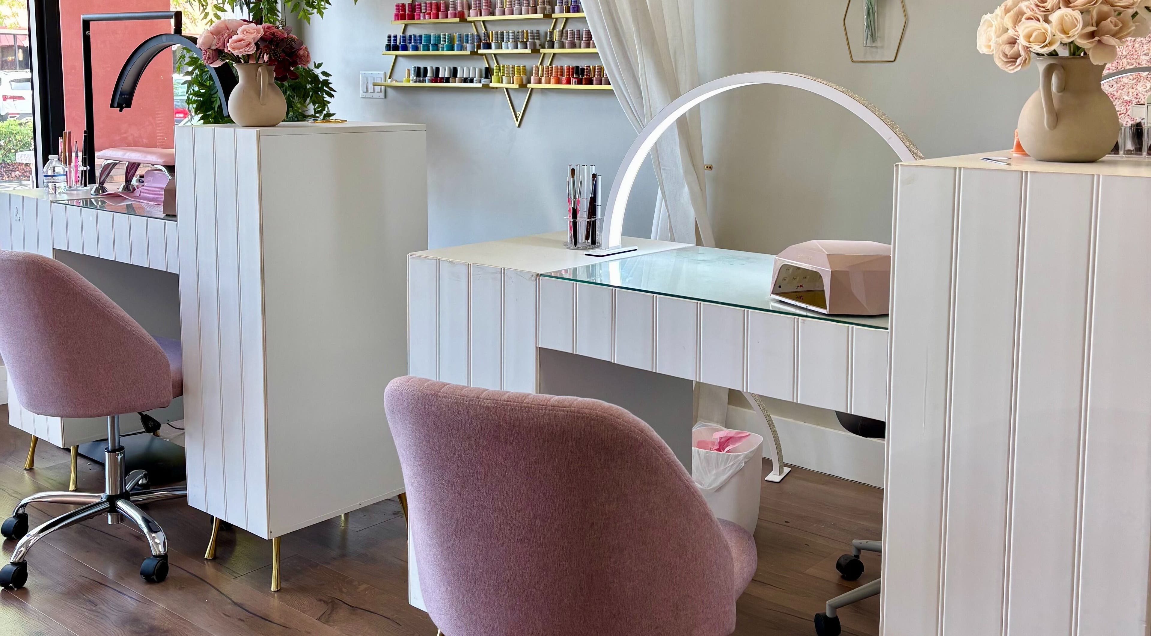 Elegant nail station at Blushed Miami, Palmetto Bay, FL, US, showcasing pink chairs and nail polish display.