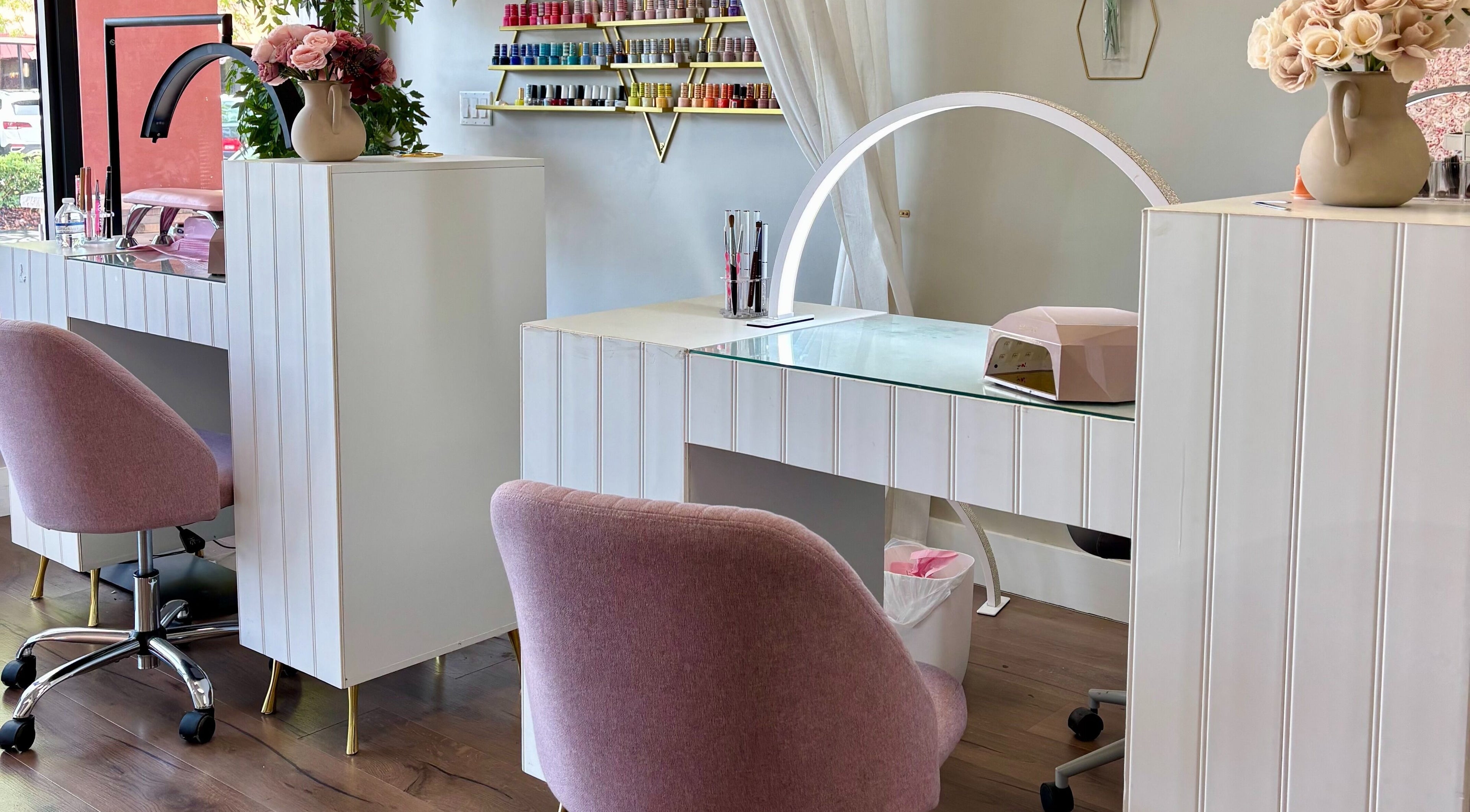 Elegant nail station at Blushed Miami, Palmetto Bay, FL, US, showcasing pink chairs and nail polish display.