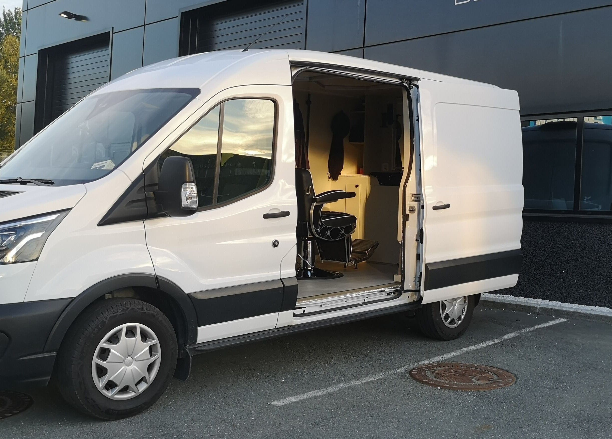 Mobil barberstol hos Barberer Olsen i Trøndelag, Trøndelag, NO, parkert utenfor en moderne bygning.