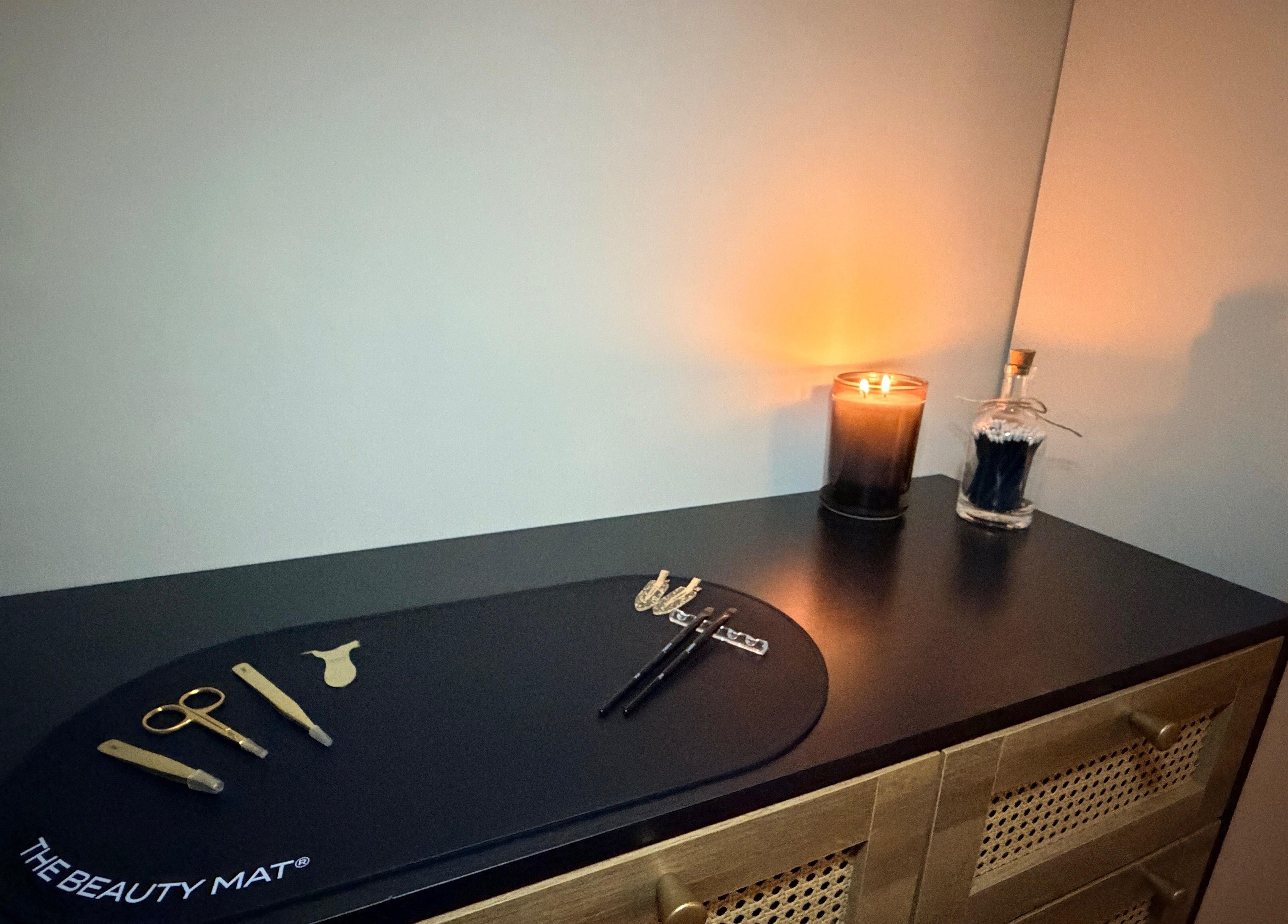 Modern beauty tools and lit candle on a chic dresser at Brows by GG, Bristol, England, GB.