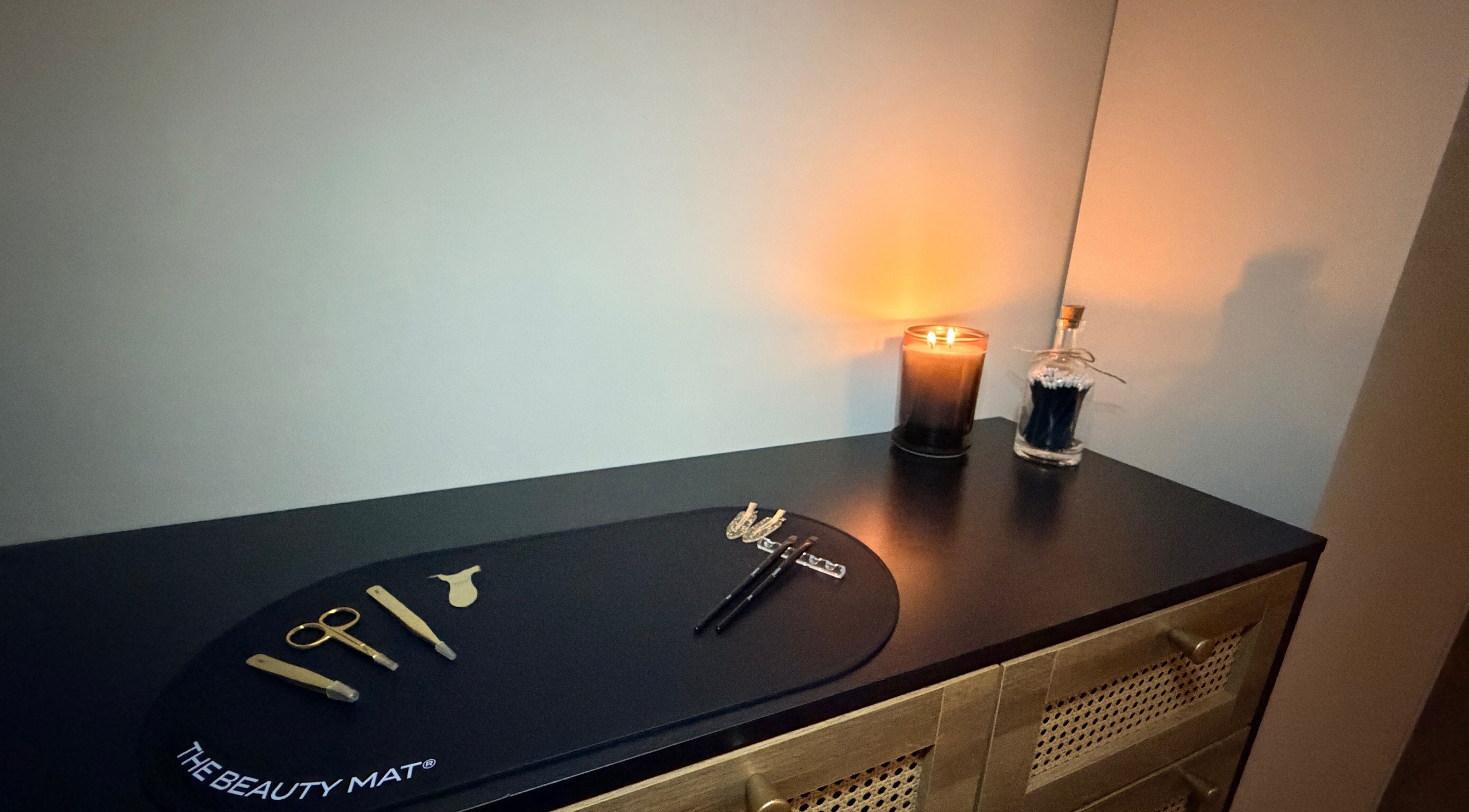 Modern beauty tools and lit candle on a chic dresser at Brows by GG, Bristol, England, GB.