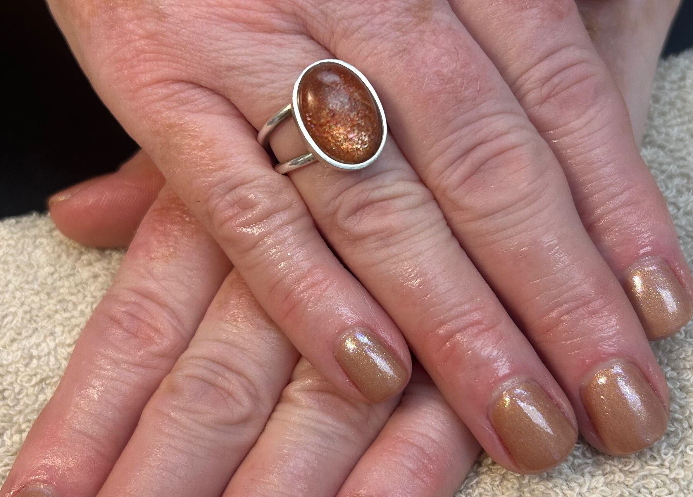 Elegant golden manicure at Glow up with Claire, Bingley, England, GB. Beautiful hand with shimmer nail polish.