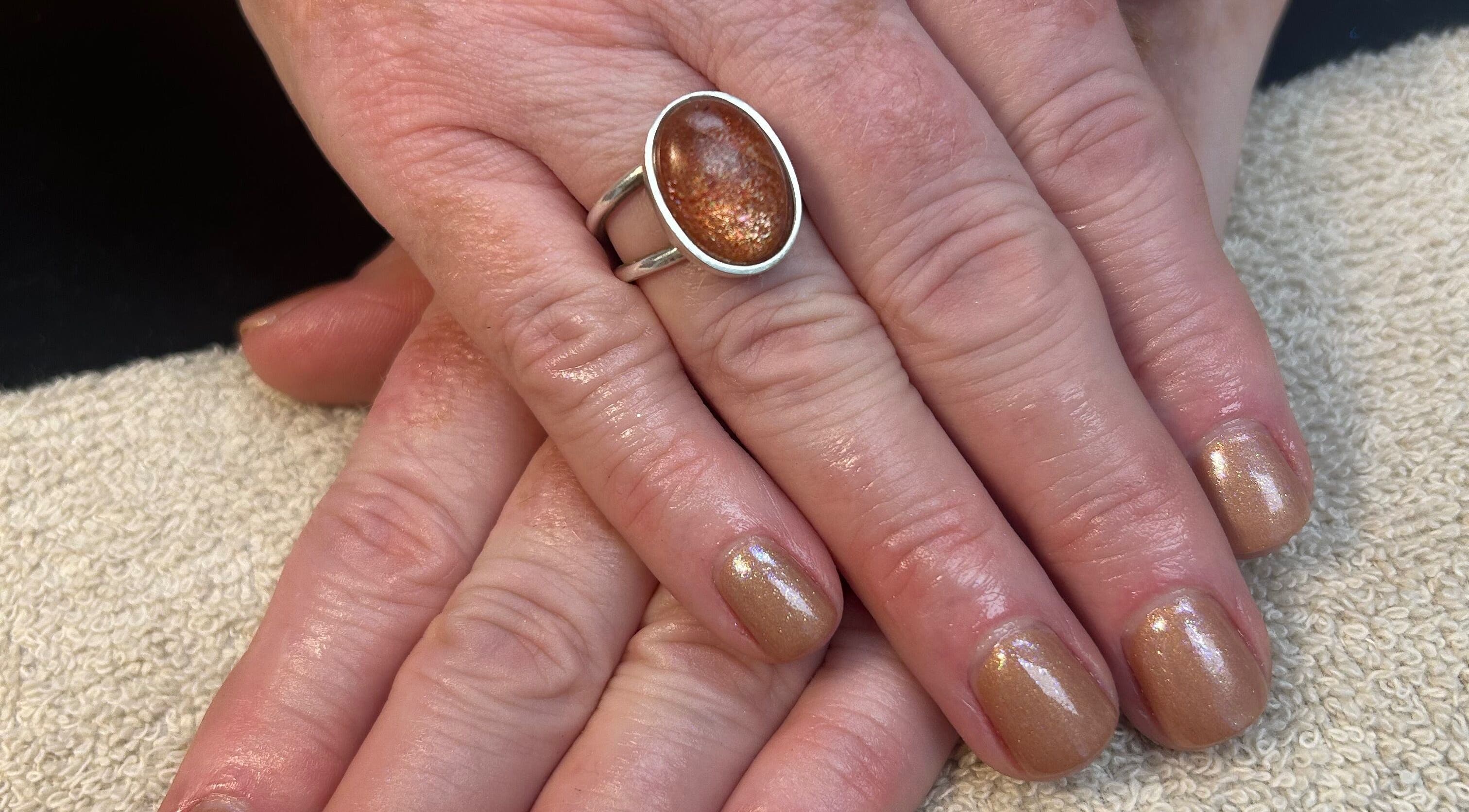 Elegant golden manicure at Glow up with Claire, Bingley, England, GB. Beautiful hand with shimmer nail polish.