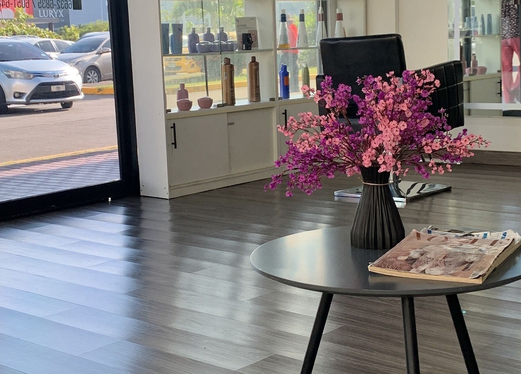Interior elegante de Capilarium Los Pueblos, Panamá. Ramo de flores en mesa junto a sillas de salón de belleza.