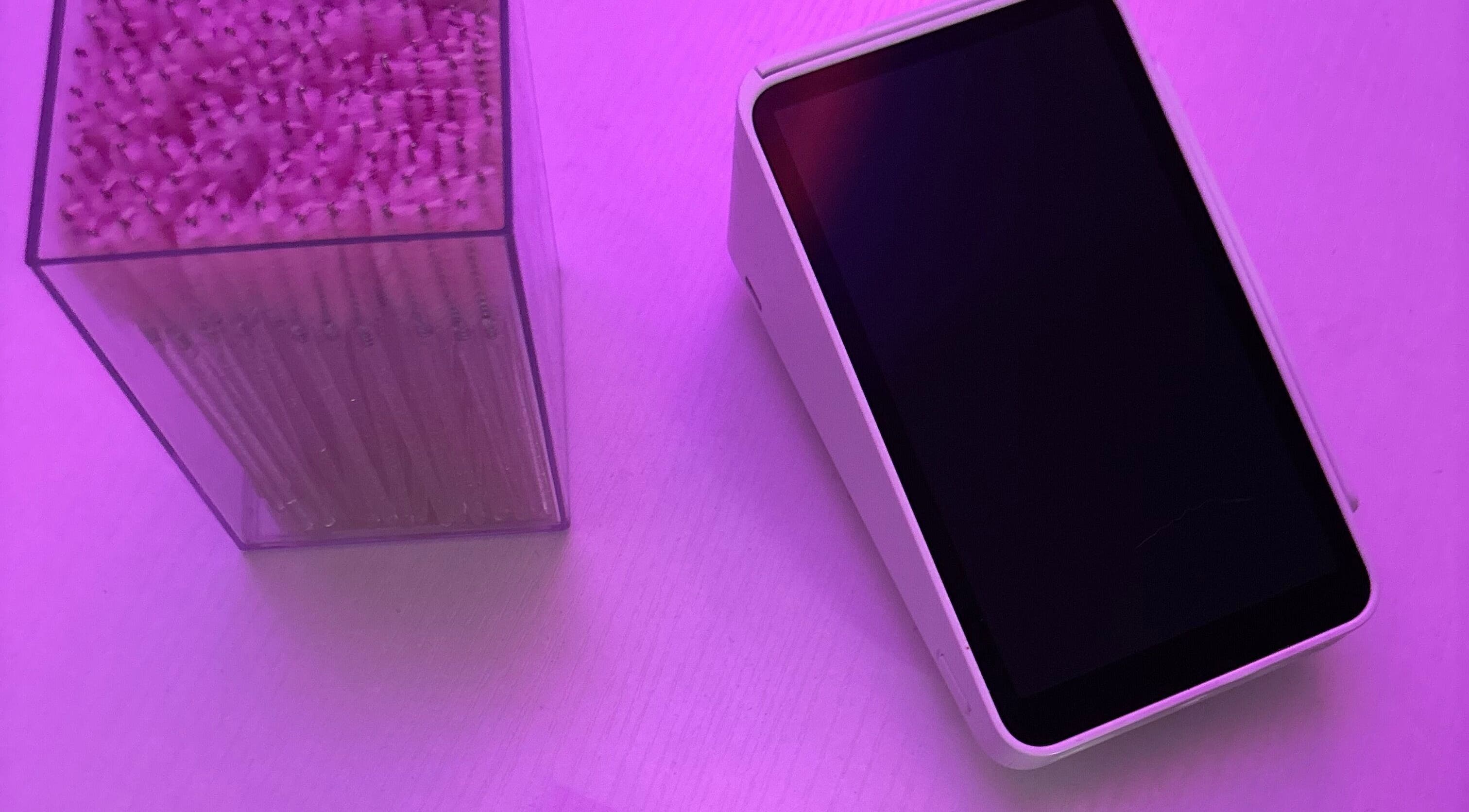 Digital tablet and cotton swabs at Lashes by Rosie, Longueuil, Québec, CA, under pink lighting for a modern vibe.