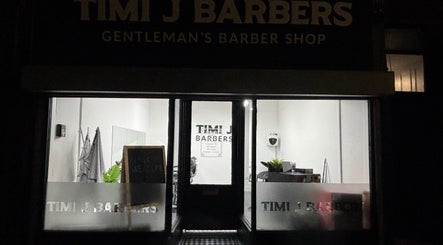 Evening view of TIMIJBARBERS shopfront in Paisley, Scotland, GB, showcasing a sleek and inviting barber ambiance.