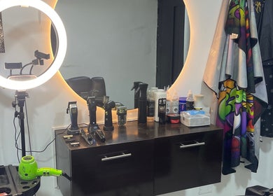 Estación de trabajo en Aguilar barber shop, Cali, Valle Del Cauca, CO con herramientas y espejo iluminado.
