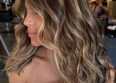 Wavy brown hair with blonde highlights by Hair by Sah in East Massapequa, New York, US.