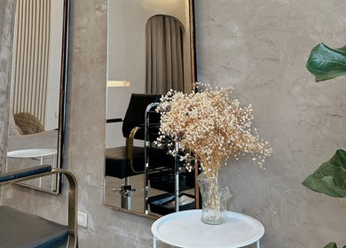 Elegant salon corner at Gorjosh By Joshua Yu, Cagayan De Oro City, featuring a mirror, chair, and flowers.