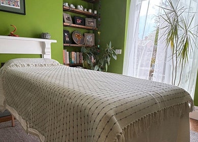 Relaxing treatment room at Better Health Kinesiology, Cardiff, Wales, GB, with green walls and a cozy bed.