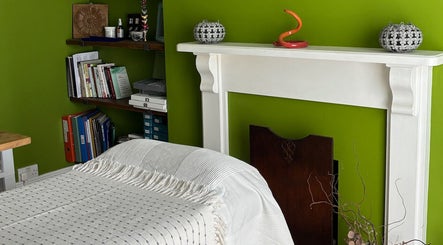 Cozy treatment room at Better Health Kinesiology, Cardiff, Wales, GB with warm decor and arranged books.