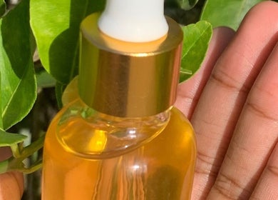 Hand houdt glanzende fles olie bij Laiss Beauty and Cosmetics, Paramaribo, Paramaribo, SR.