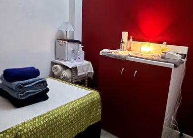 Cozy massage room at Sasima Thai Massage Windsor featuring a red accent wall and soft lighting, Windsor, England, GB.