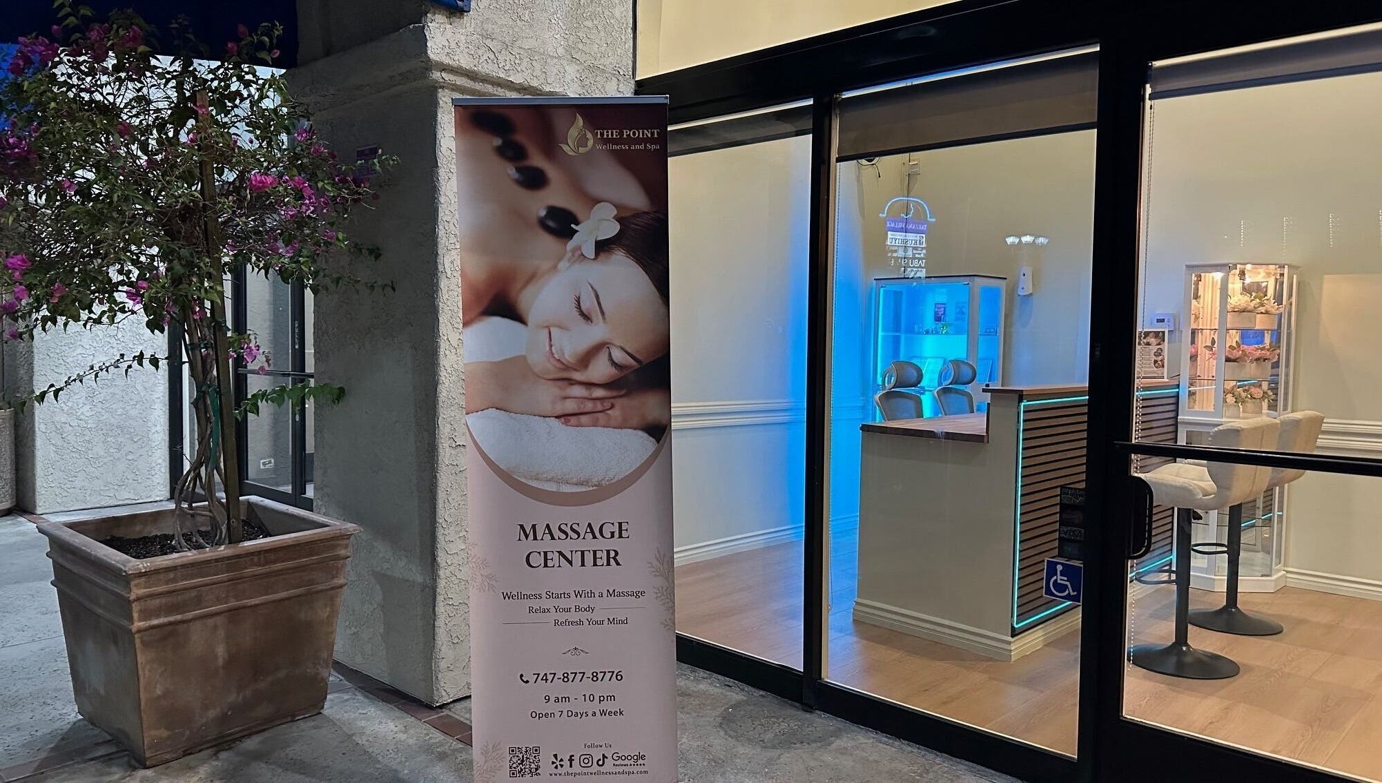 Entrance of The Point Wellness and Spa in Tarzana, California, US with a massage banner and cozy interior.