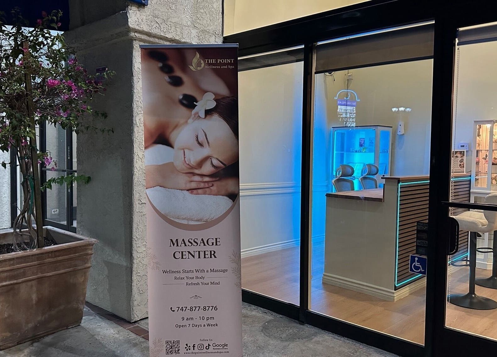 Entrance of The Point Wellness and Spa in Tarzana, California, US with a massage banner and cozy interior.