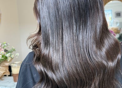 Elegant silky hair waves styled at TJJ_Hair in Crawley, England, GB with floral decor in the background.