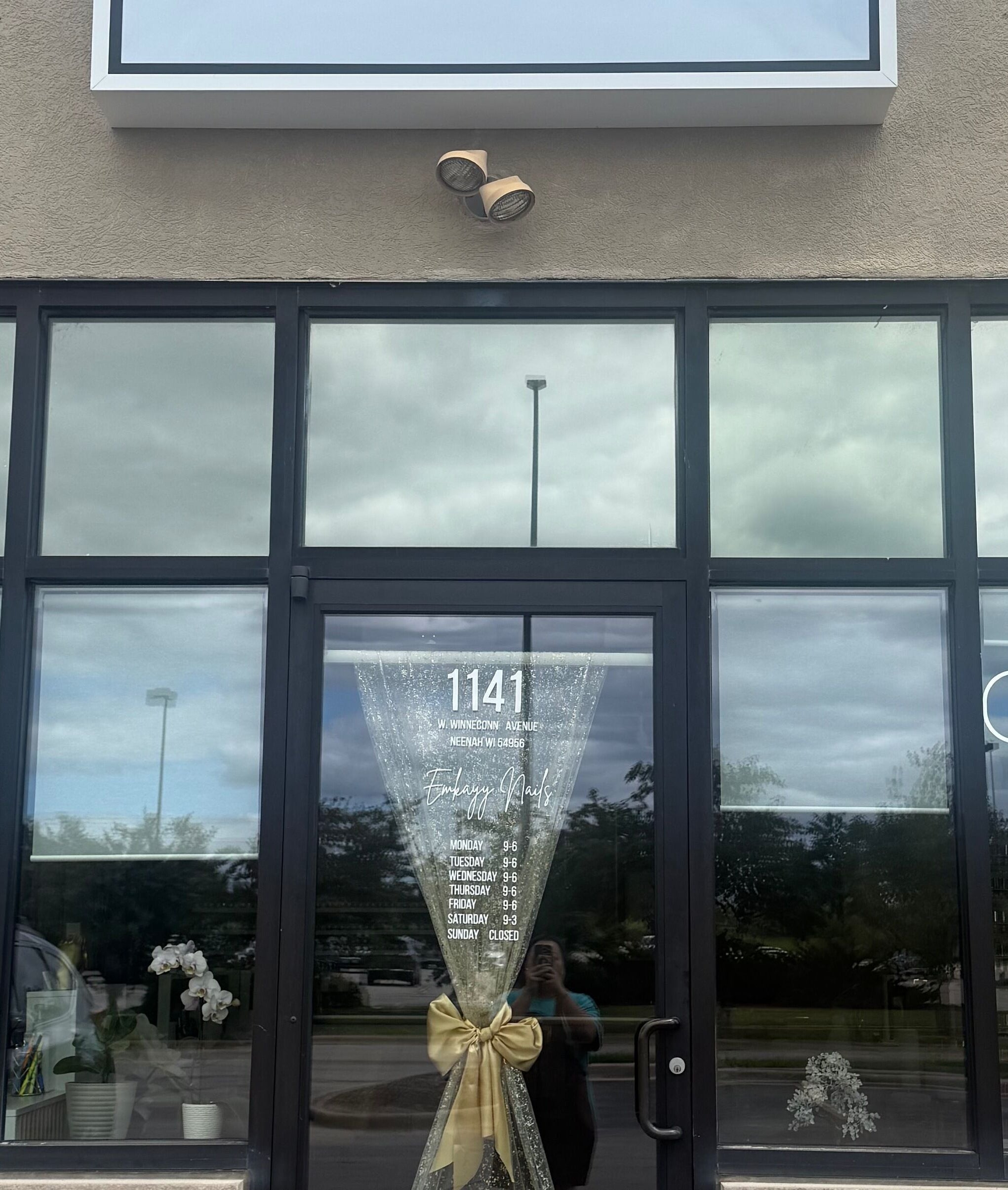 Front view of Emkayy Nails, Neenah, Wisconsin, US, with a welcoming open sign and elegant glass decor.