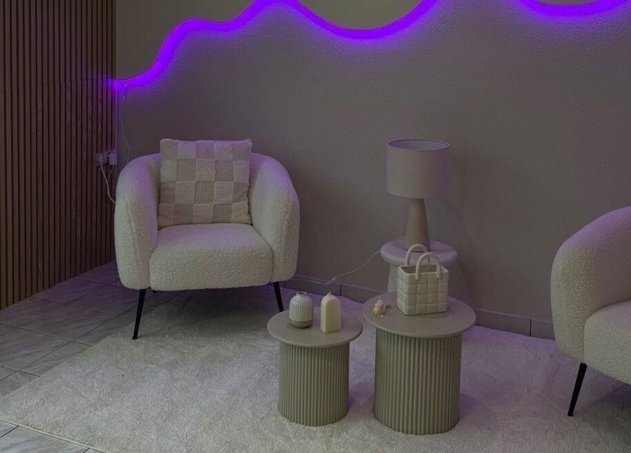 Salon élégant à Maison Perséa, Le Controis-en-sologne, avec néons violets et fauteuils confortables.