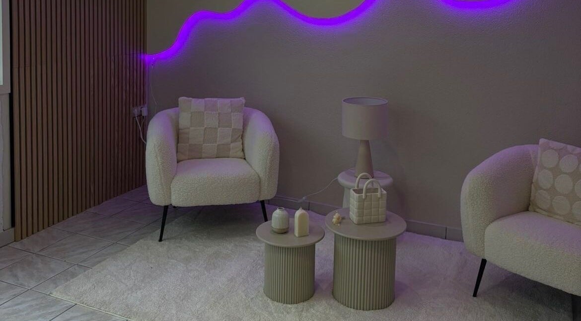 Salon élégant à Maison Perséa, Le Controis-en-sologne, avec néons violets et fauteuils confortables.