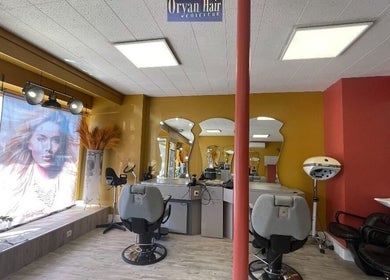 Intérieur de Oryan Hair à La Loupe, Centre-val De Loire, FR, montrant fauteuils de coiffure et miroirs élégants.