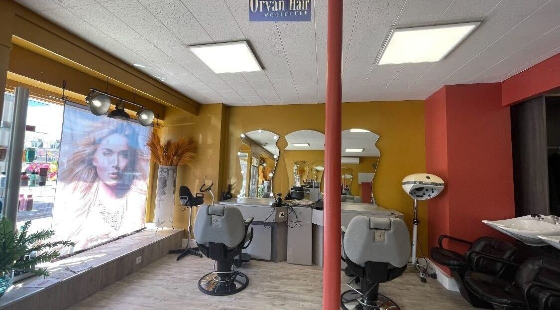 Intérieur de Oryan Hair à La Loupe, Centre-val De Loire, FR, montrant fauteuils de coiffure et miroirs élégants.