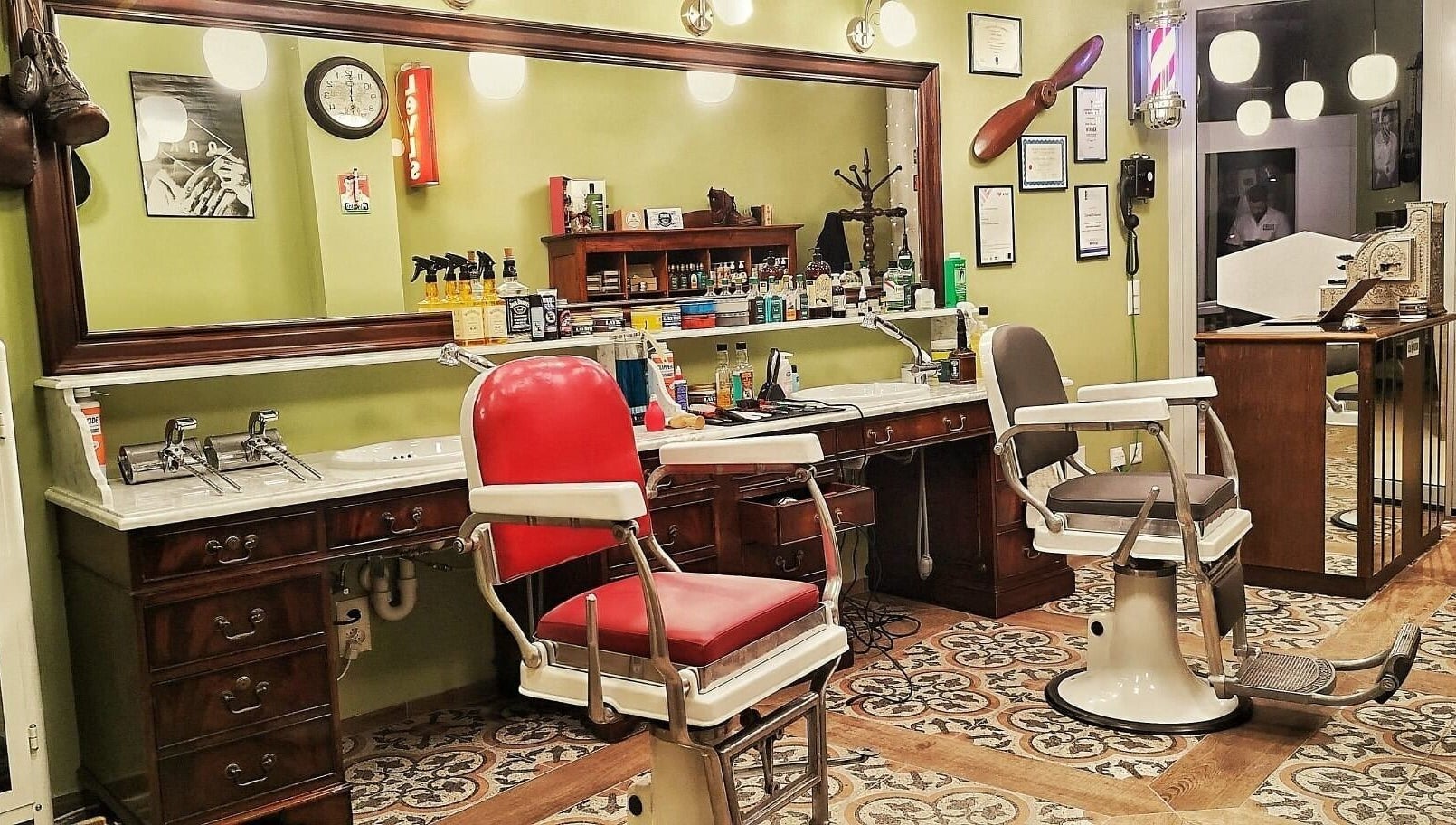 Interno elegante di Buddies Barbershop a Losone, Ticino, CH con poltrone vintage e specchio grandi.