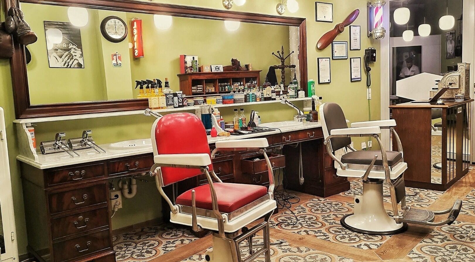 Interno elegante di Buddies Barbershop a Losone, Ticino, CH con poltrone vintage e specchio grandi.