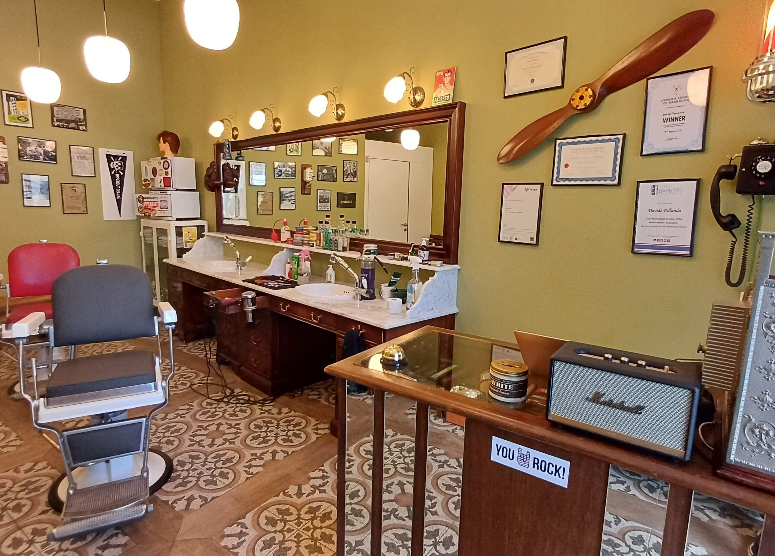 Interno vintage di Buddies Barbershop a Losone, Ticino, CH con sedie da barbiere e specchi eleganti.