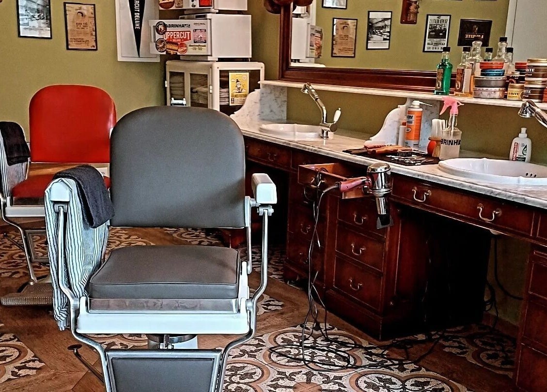 Interno di Buddies Barbershop a Losone, Ticino, CH con sedia vintage e arredi classici.