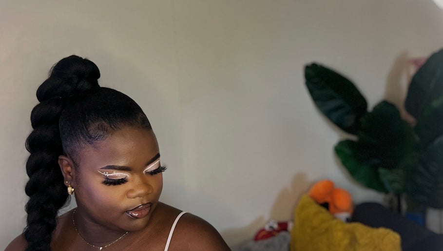 Elegant woman with braided hairstyle at Allure Beaute’, St. Johns, AG showcasing bold, glamorous makeup.