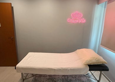 Relaxing treatment room at SugarViz, Singapore, SG, with a massage table and soft lighting.