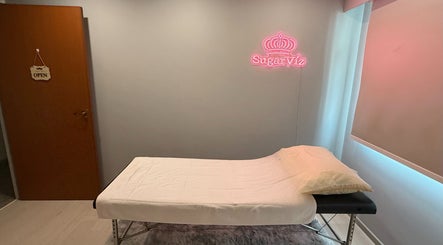 Relaxing treatment room at SugarViz, Singapore, SG, with a massage table and soft lighting.