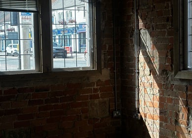 Sunlit brick interior of Snowden Barbers in Scunthorpe, England, GB, with views of the street outside.