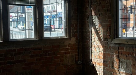 Sunlit brick interior of Snowden Barbers in Scunthorpe, England, GB, with views of the street outside.