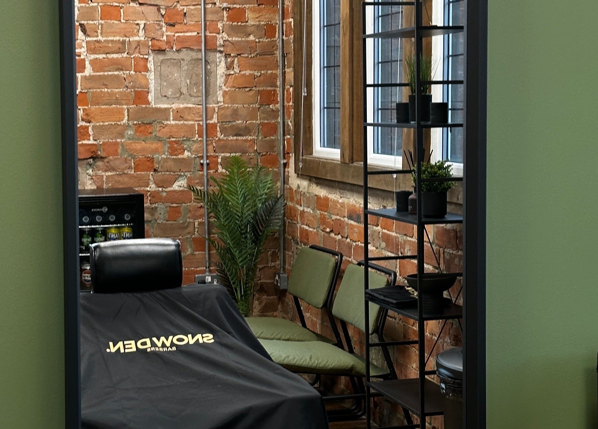 Stylish barber chair at Snowden Barbers, Scunthorpe, England, GB with exposed brick walls and modern decor.