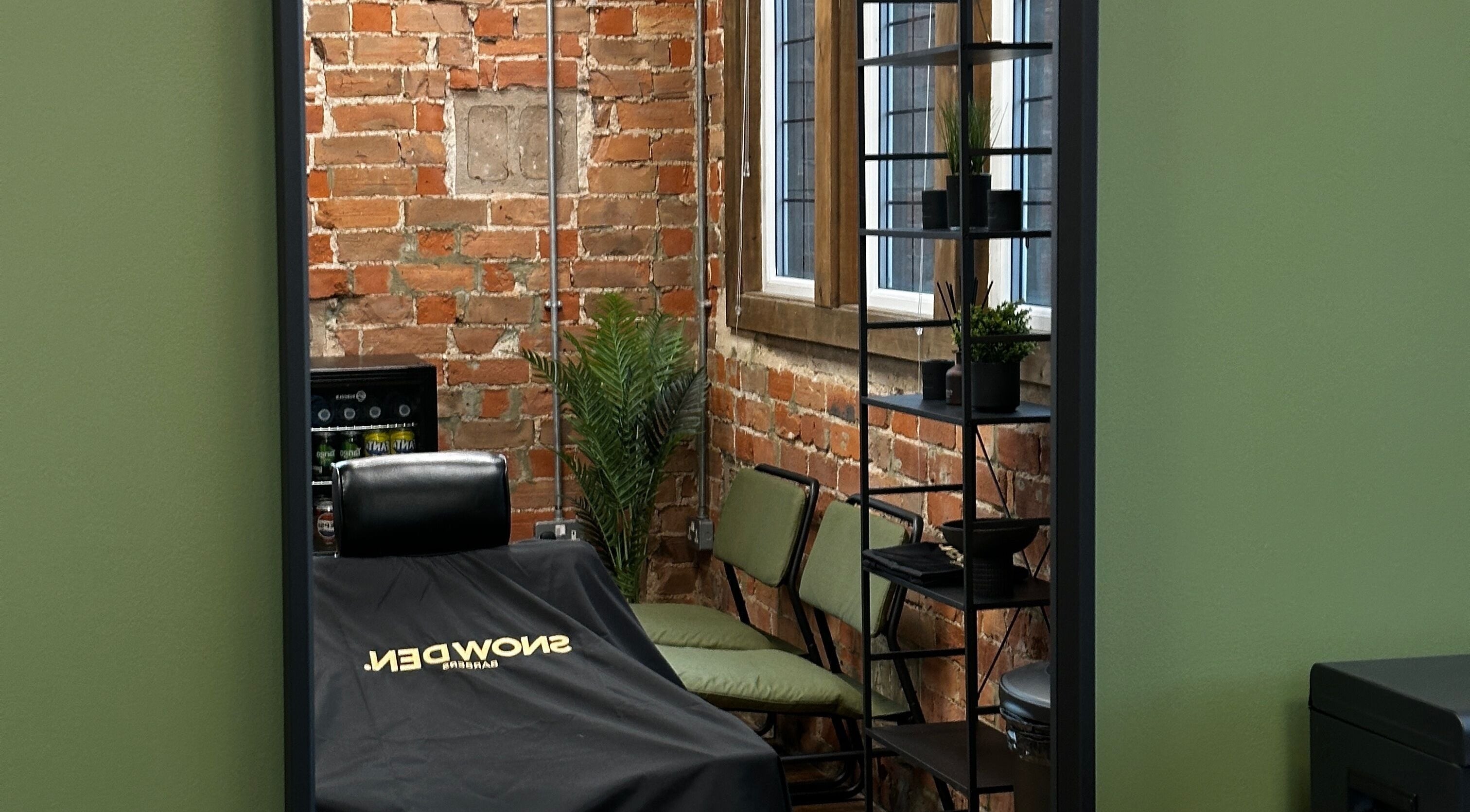 Stylish barber chair at Snowden Barbers, Scunthorpe, England, GB with exposed brick walls and modern decor.
