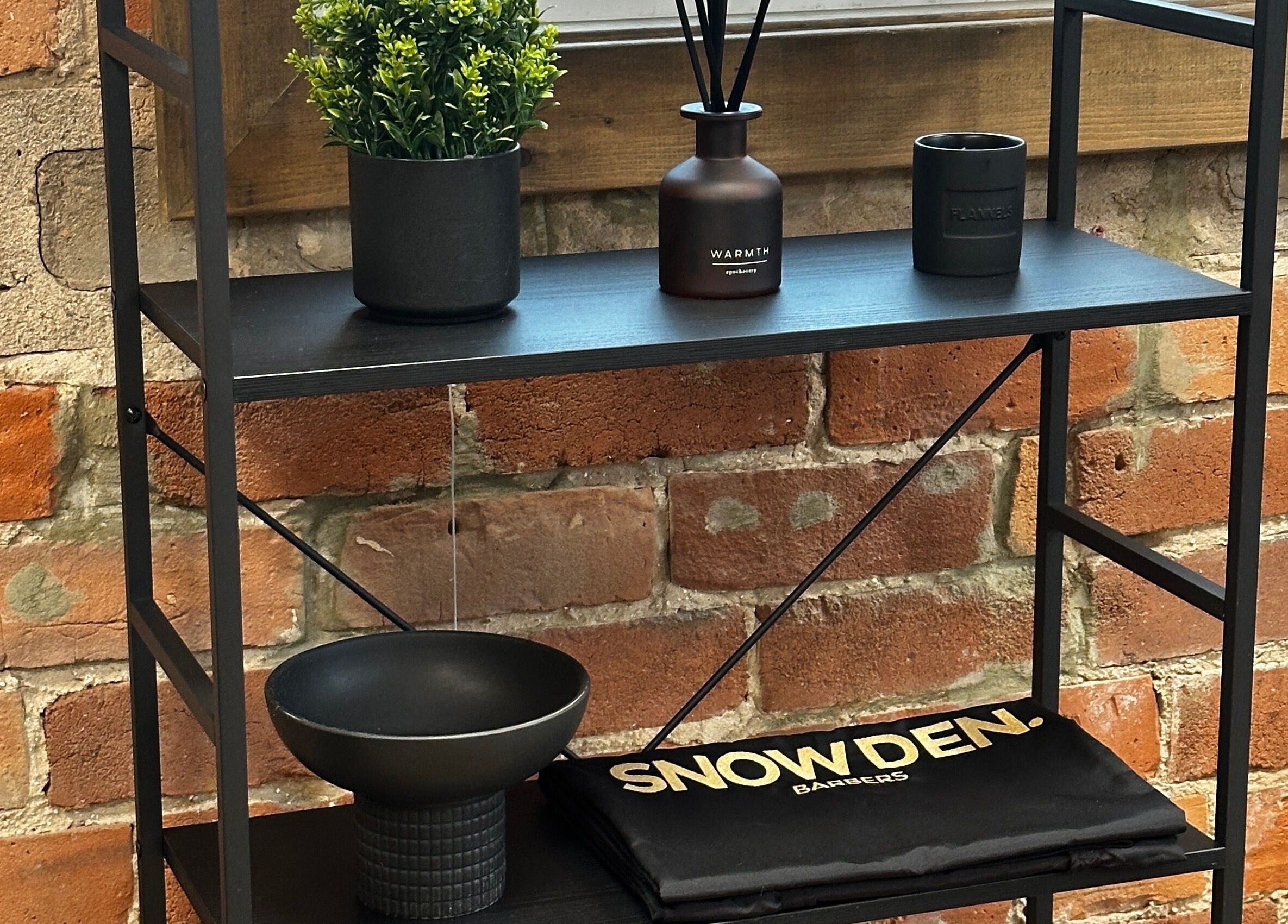 Modern black shelf at Snowden Barbers in Scunthorpe, England, GB, with plants and grooming items.